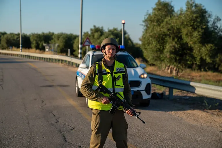 שוטר מהמשטרה הצבאית חמוש עומד לצד ניידת בכביש