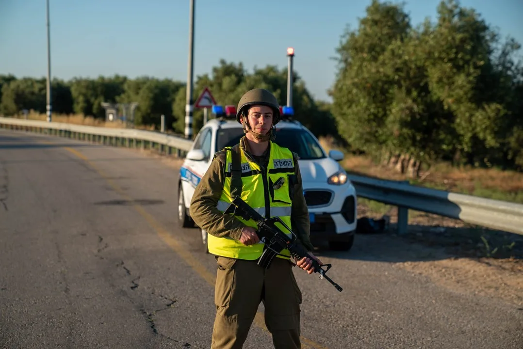 שוטר מהמשטרה הצבאית חמוש עומד לצד ניידת בכביש