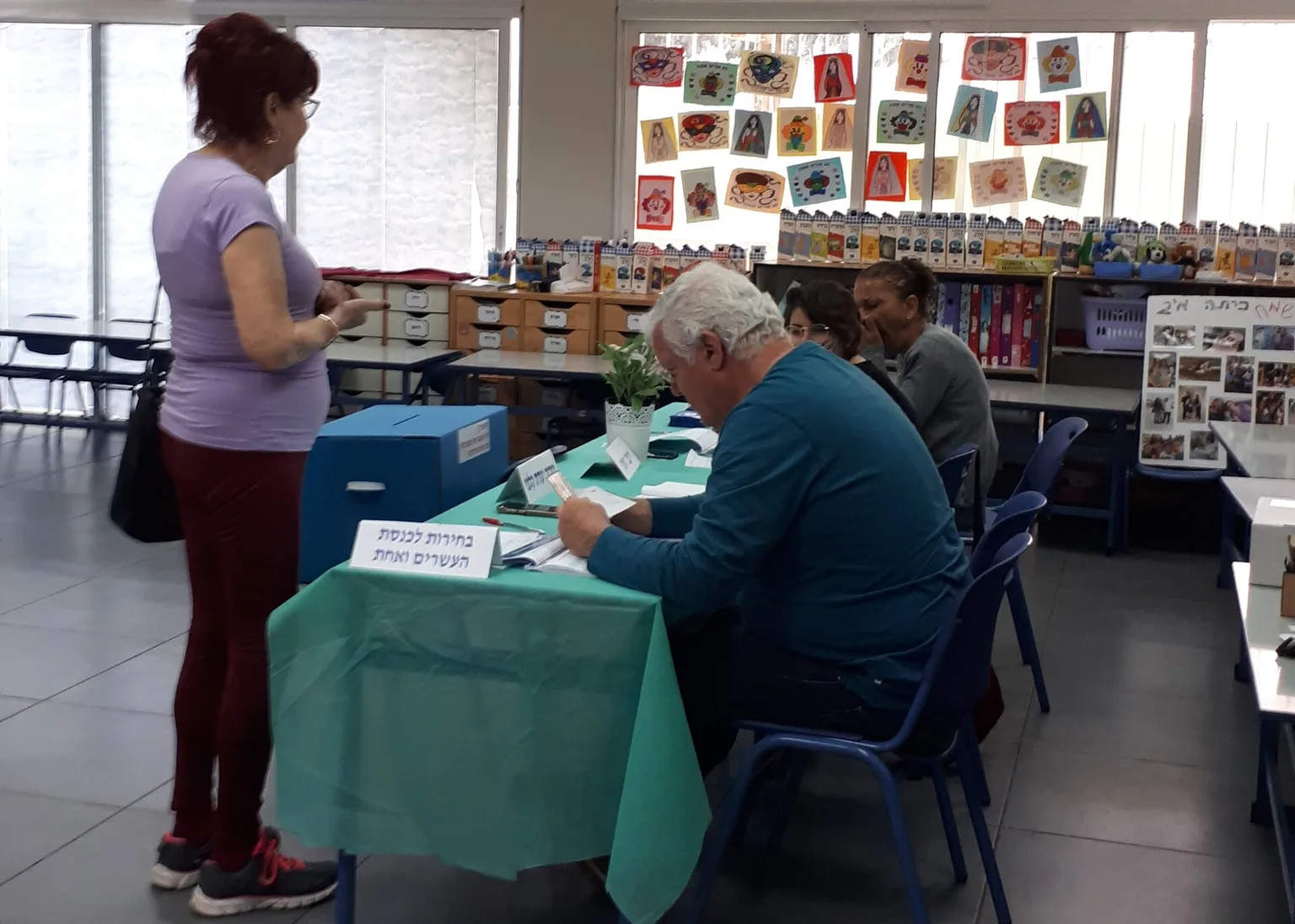 מצביעה בקלפי בבחירות בישראל לצד חברי ועדת הקלפי