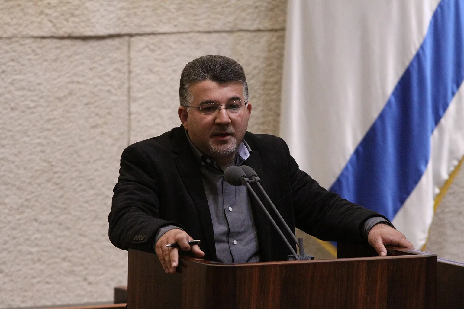 ח״כ יוסף ג׳בארין נואם מדוכן הכנסת, לצד דגל ישראל