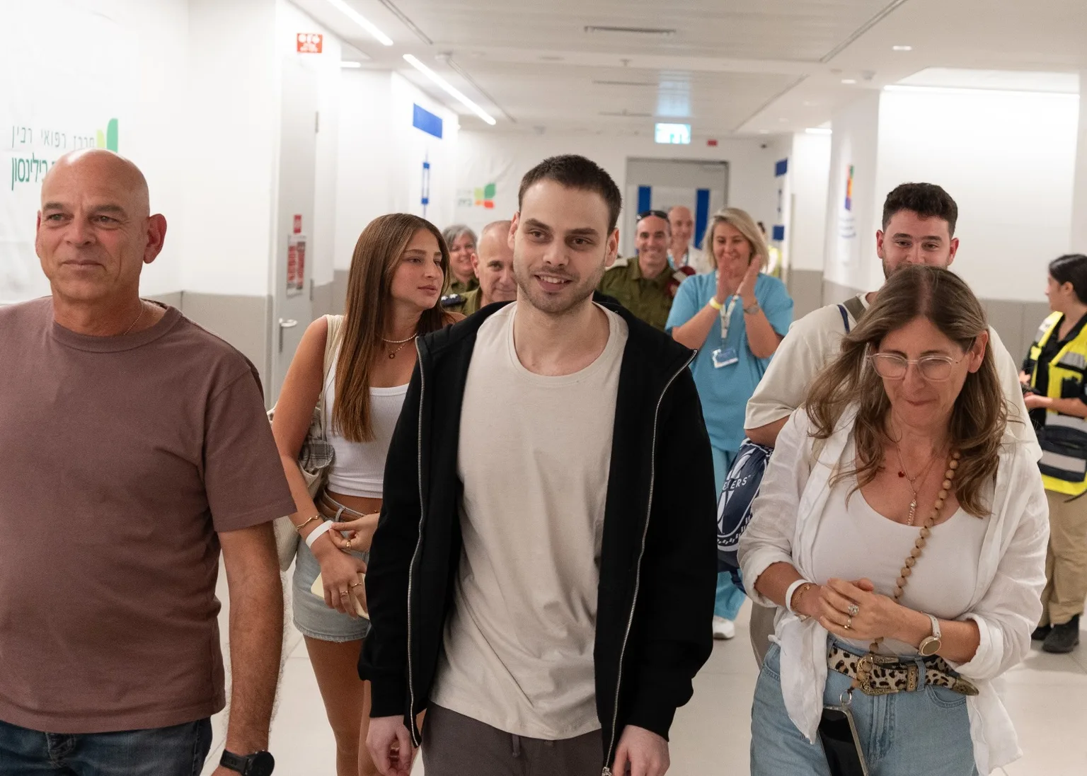 אלון אהל צועד במסדרון בית חולים לאחר שחרורו מהשבי, מוקף בבני משפחה ואנשי צוות