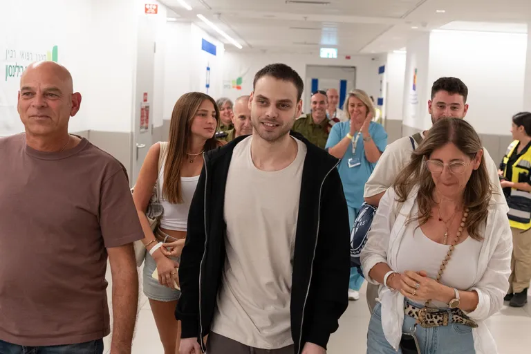 אלון אהל צועד במסדרון בית חולים לאחר שחרורו מהשבי, מוקף בבני משפחה ואנשי צוות